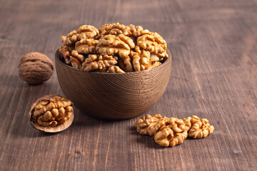 Walnuts nuts in a bowl on wooden background