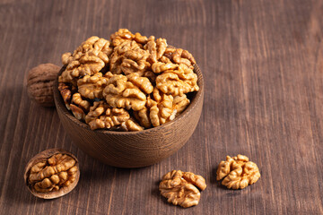 Walnuts nuts in a bowl on wooden background
