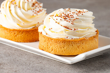 Lemon tartlets with whipped cream, sprinkles and chocolate chips on white background