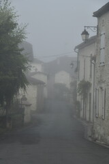 Rue typique dans le brouillard au bourg de Champagne au Périgord Vert 