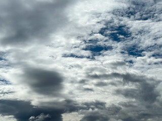 Fototapeta premium Stormy sky with dark, snowy clouds on a spring day. Clouds are floating across the sky. Dramatic clouds. Dark blue clouds swiftly floating across blue sky. Sky texture, abstract nature background.