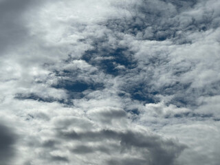 Stormy sky with dark, snowy clouds on a spring day. Clouds are floating across the sky. Dramatic clouds. Dark blue clouds swiftly floating across blue sky. Sky texture, abstract nature background.