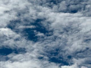 Stormy sky with dark, snowy clouds on a spring day. Clouds are floating across the sky. Dramatic clouds. Dark blue clouds swiftly floating across blue sky. Sky texture, abstract nature background.