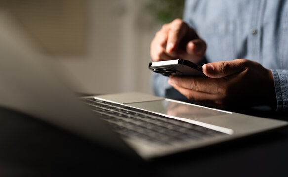 Business man using and typing keyboard of laptop computer on office desk with mobile smartphone communicates on internet technology. Workplace, professional busy working on new job project idea.
