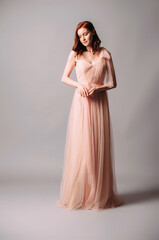 Elegant bridesmaid’s two-layer maxi gown. Gorgeous young sexy lady with curly hairstyle. Ivory...