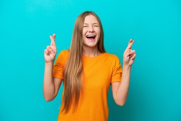 Young Russian woman isolated on blue background with fingers crossing
