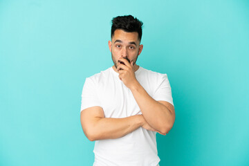 Young caucasian man isolated on blue background surprised and shocked while looking right