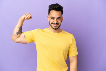 Young caucasian man isolated on purple background doing strong gesture