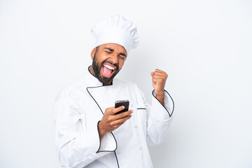 Young Brazilian chef man isolated on white background with phone in victory position