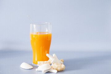 A vibrant bottle of refreshing orange juice is paired with white stones on a blue light background.