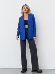 Striking female model showcasing vibrant blue blazer in studio fashion shoot