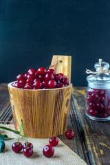 wooden barrel with ripe cherries on old wooden table.
