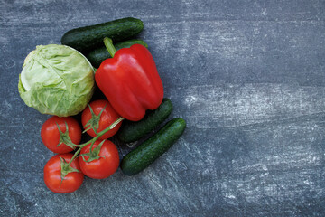 Freshly veggies lying on a dark surface top view. tomatoes, cucumbers, cabbage, bell peppers. Concept of healthy food, fresh ingredients and vegetarian cuisine. 