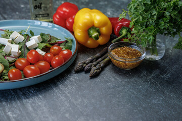 fresh  salad on a table with ingredients for cooking.vegetarian food.salad of fresh vegetables, greens, cheese with bell peppers, asparagus, mustard seeds, healthy eating
