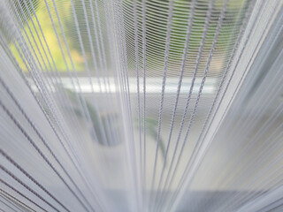 Close-up view of sheer curtains filtering sunlight in a home setting, creating a soft and serene ambiance in the background, ideal for interior decor themes.