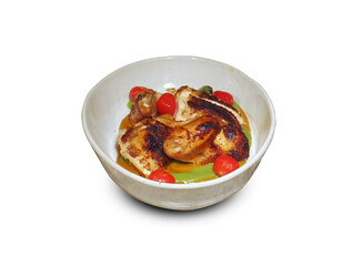 Grilled chicken piri piri in a ceramic bowl with cherry tomatoes and green sauce, isolated 