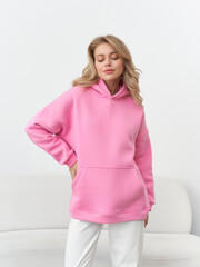Fashionable model poses in a stylish pink hoodie in a modern studio setting