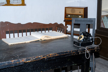 The interior of an old town hall in the country with a telephone and a clock on the desk and an old radio in the back