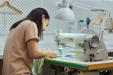 A Focused Seamstress Diligently Working with a Sewing Machine in Her Creative Workspace