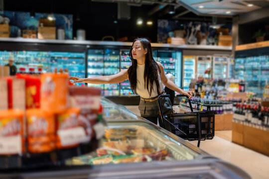Customer selecting groceries in supermarket, shopping for refrigerated food in grocery store