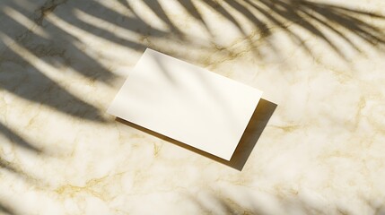 Blank business card placed on a light marble surface with sunlight streaming in from the left