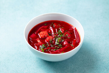 Borsch, beetroot soup in a bowl. Blue background. Close up.