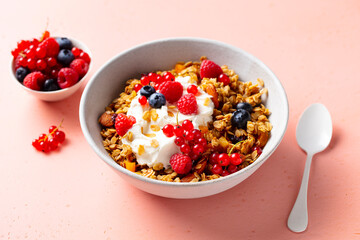 Healthy breakfast. Granola, muesli with yogurt and fresh berries. Pink background. Close