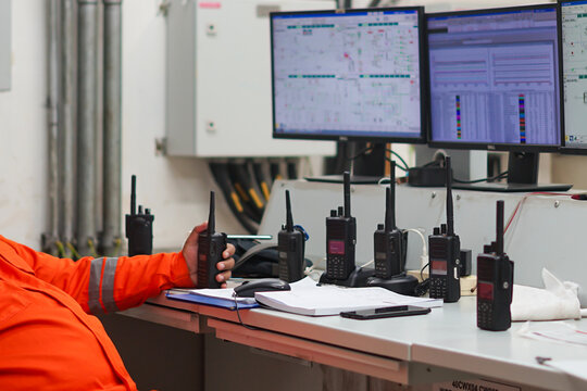 Operator actively monitoring systems and communicating via walkie talkie in industrial control room