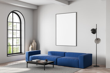 Modern interior with blue sofa and empty framed poster on clean white wall in stylish living room with natural light and minimalist decor elements. 3D Rendering
