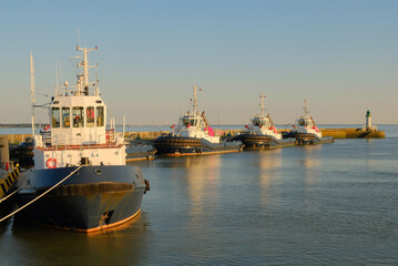 Fleet of Port Tugboats Docked in Golden Hour Light at Industrial Harbor