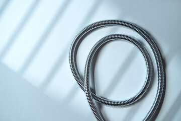 Stainless steel shower hose elegantly placed on soft surface.