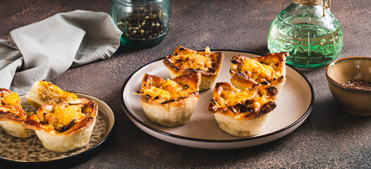 Mini tartlets with caramelized onions and cheese on a plate on a table web banner