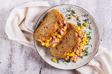 Close up of delicious sandwiches with tuna, corn and greens on grain bread top view