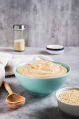 Sesame tahini in a bowl and sesame seeds in a bowl on the table vertical view