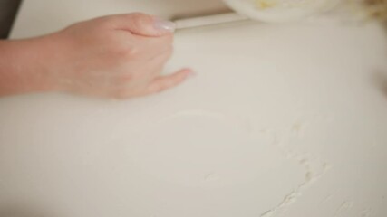 close up hand view of bakers adjusting glass bowl filled with dough while cleaning scattered flour underneath, another person assists in wiping surface during kitchen baking process