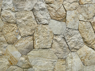 Close up of natural random cut beige yellow cobble stone flattened on a surface. Rough flagstone and gravel stacked randomly and cemented, for floor or wall finishes. Seamless background texture.    