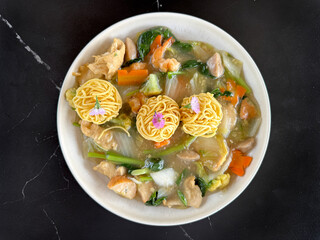 Close up of Chinese food called Cap Cay or mixed vegetables in English, with dried noodle ball and edible flowers. Cap Cay is a famous Hokkian Chinese cuisine, cooked worldwide. Delicious food.