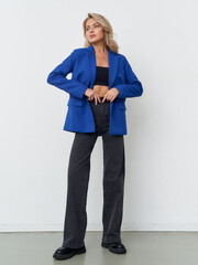 Stylish model in a vibrant blue blazer poses confidently in a minimal studio setting