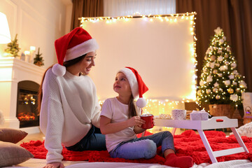 Mother and daughter near video projector screen at home. Cozy Christmas atmosphere