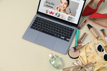 Laptop with beauty blog web site, shoes, accessories and makeup products on beige background, above...