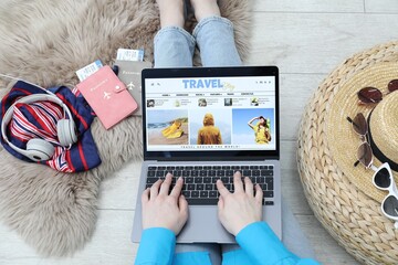 Blogger using laptop with travel blog web site on floor indoors, above view