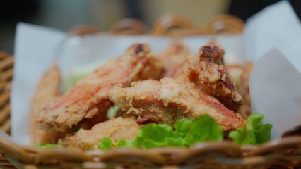 Close-up of crispy fried chicken wings served on fresh lettuce in a woven basket, ideal for food and culinary themes. Delicious Snack or Appetizer Perfect for Any Occasion