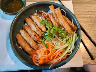 Vietnamese noodle bowl, bun cha in black bowl with chopstick on wooden table