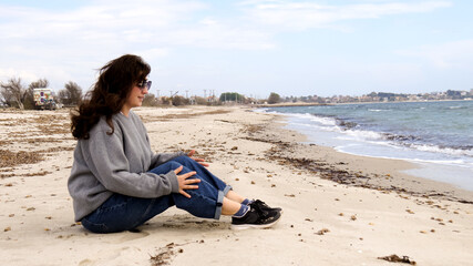 Woman sitting on a sandy beach, looking at the sea -calm moment