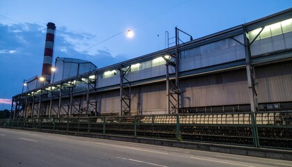 Obraz premium Industrial Factory Building at Dusk with Smokestack and Street View