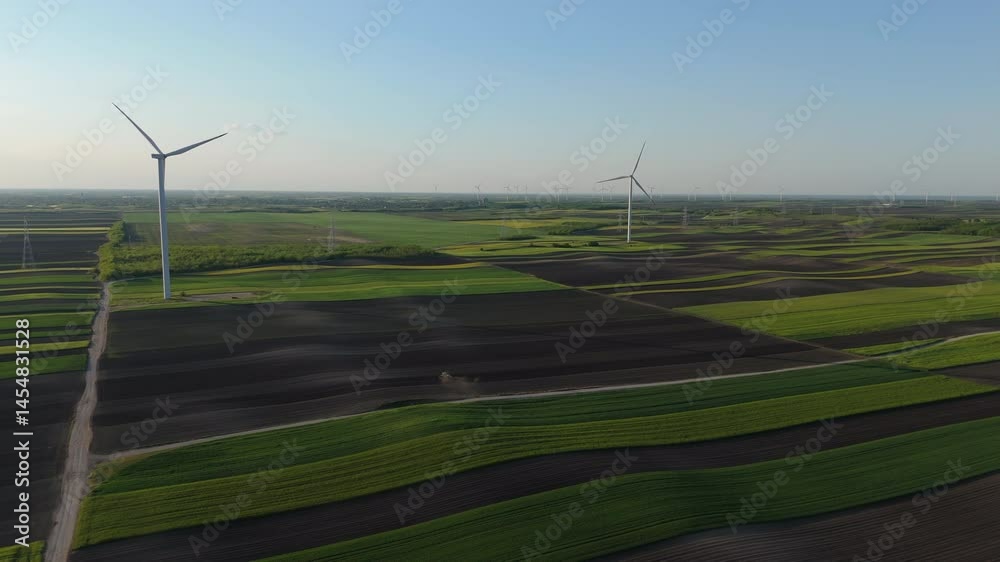 Aufkleber Agricultural tractor is working on the field with wind turbines. Aerial view	
