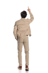 Naklejka premium behind view of casual guy pointing finger to the sky while stepping