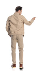 behind view of young guy pointing finger and looking to side while walking