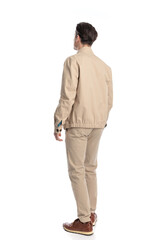 back view of casual young man in beige jacket walking