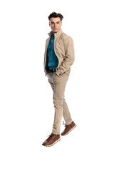 Naklejka premium confident casual man in beige jacket walking with hands in pockets